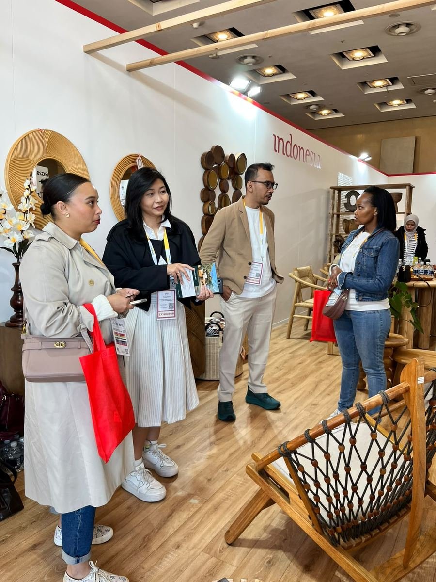 Exhibitors talking with South African visitors next to a teak rope chair at the Indonesia Pavilion
