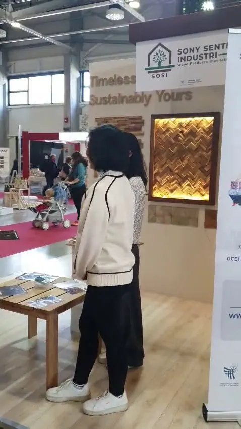 SOSI booth at HOMEDesign Budapest 2025 with backlit herringbone teak wall panel, Timeless Sustainably Yours wall text and company banner