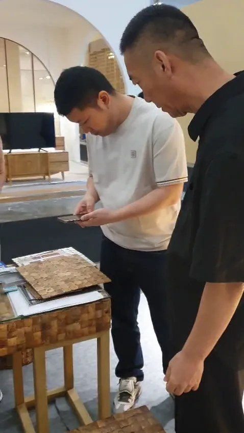 Visitor photographing coconut shell mosaic panel samples on a small mosaic pedestal table at the SOSI IFEX booth