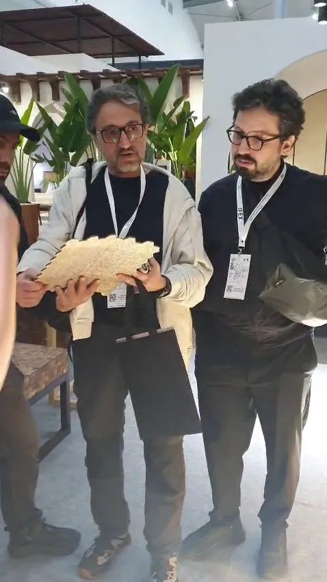 Two visitors examining a light hexagonal mosaic wall panel sample at the SOSI booth during IFEX